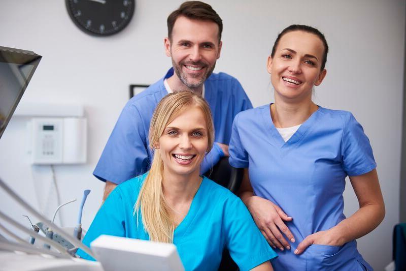 Team of medical assistants smiling at desk