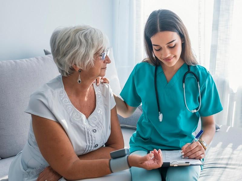 Medical assistant smiling with elderly patient taking patient history