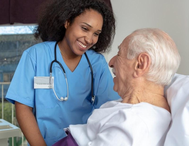 Medical assistant wearing stethoscope smiling with elderly patient