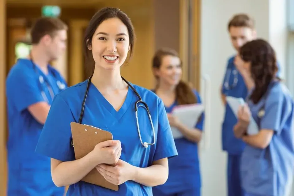 Smiling Registered Nurse with Clipboard with Nurses in Background